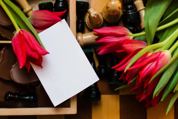 Bukiet, czerwone tulipany, serduszka czekoladowe i szachy — Zdjęcie stockowe