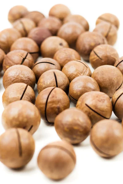 Raw not peeled whole macadamia nuts isolated on white — Stock Photo, Image