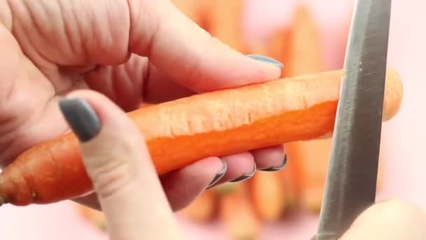 Processo Descascamento Cenoura Com Uma Faca Fundo Rosa Vista Cima — Vídeo de Stock