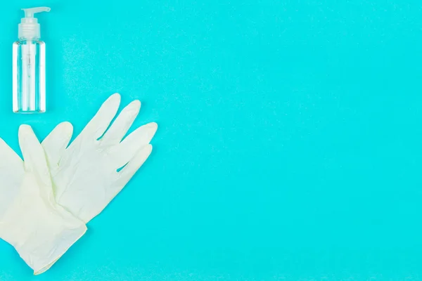 Luvas de látex branco e gel higienizador de mão no fundo azul . — Fotografia de Stock