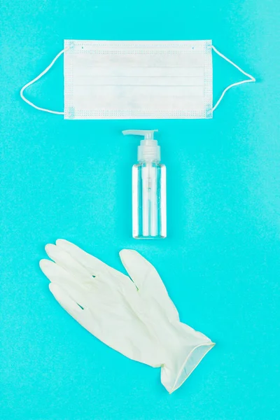 Máscara médica, luvas de látex branco e gel higienizador de mão no fundo azul . — Fotografia de Stock