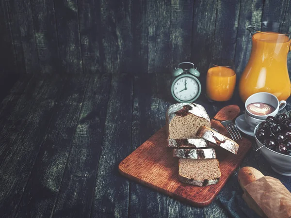 Bröd, apelsinjuice, körsbär och klocka. — Stockfoto