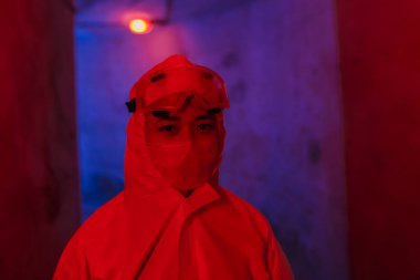 Koronavirüsten korunmak için beyaz kimyevi giysili bir virüs uzmanı, bir maske ve gözlük.