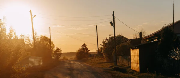 Gün batımında güzel kırsal panoramik manzara. Ahşap evler, demir garaj ve tahta kazıklar. (124; KOROVYAKOVA, SVERDLOVSKAYA OBLAST - 9 Mayıs 2020.