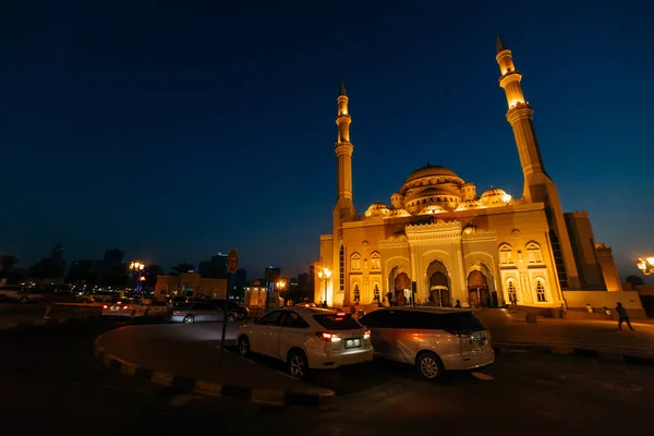 Gece geç saatlerde karanlık gökyüzüne karşı sarı ışıklı iki kule ve kubbeli cami; UNITED ARAB EMIRATES, SHARJAH - 17 Ekim 2017.