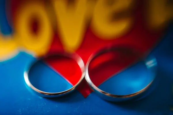 Anillos Boda Sobre Fondo Azul Rojo Con Inscripción Amarilla Love — Foto de Stock