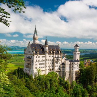Bavyera, Neuschwanstein, Almanya 'daki ünlü peri masalı. Mavi gökyüzü ve beyaz bulutlarla panoramik manzara.