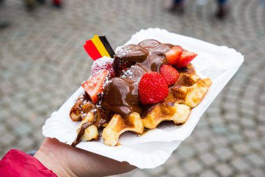 Çikolata soslu ve çilekli Belçika waffle 'ı, Bruges şehrinin arka planı, Belçika.