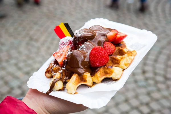 Belgium waffle with chocolate sauce and strawberries, Bruges city background, Belgium.