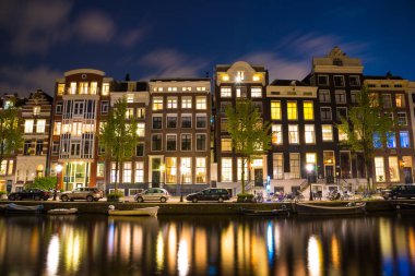 Amsterdam'da güzel bir gece. gece aydınlatma bina ve su kanalına yakın tekneler.