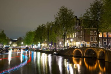 Amsterdam cityscape kanal, köprü ve ışıklı akşam alacakaranlık Ortaçağ evleri ile gece manzarası. Amsterdam, Hollanda