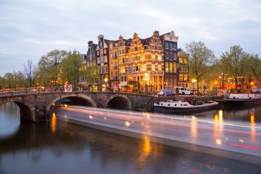 Amsterdam, Hollanda - 20 Nisan 2017: Amsterdam kanal, köprü ve tipik evleri, tekneler ve bisiklet mavi twilight saat, Felemenk, Hollanda akşam sırasında.