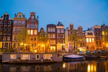 Amsterdam cityscape kanal, köprü ve ışıklı akşam alacakaranlık Ortaçağ evleri ile gece manzarası. Amsterdam, Hollanda