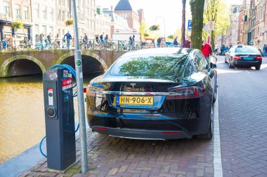 Amsterdam, Hollanda - 19 Nisan 2017: Amsterdam'da bir kanal tarafından sokakta bir şarj istasyonu şarj A Tesla Model S elektrikli otomobil.