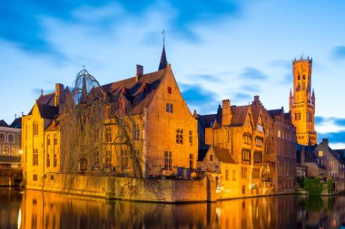 Bruges, Belçika - 17 Nisan 2017: Rosary Rıhtımı - Rozenhoedkaai ve Belfry Alacakaranlıkta. Bruges, Belçika 'daki bir ortaçağ peri masalından bir sahne