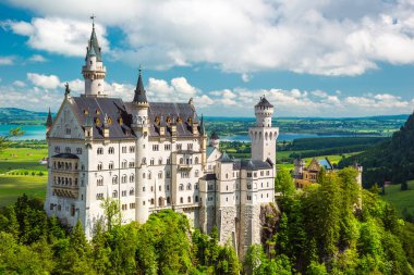 Bavyera, Neuschwanstein, Almanya 'daki ünlü peri masalı. Mavi gökyüzü ve beyaz bulutlarla panoramik manzara.