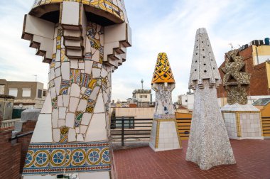 Barcelona, İspanya - 20 Eylül 2014: Guell Sarayı 'nın çatısı tasarımı - Gaudi Chimney: kırık fayans mozaikleri ve garip dekore edilmiş bacalar ilk çalışmalarında açıkça görülmektedir..