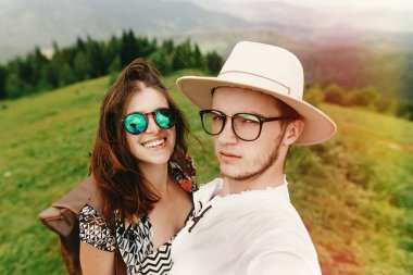 Çift şık hipster seyahat ve dağın tepesinde gülümseyen