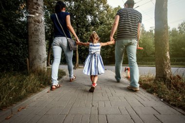 parents holding hands with daughter  clipart