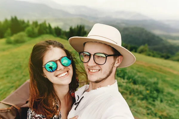 Elegante pareja hipster viajando y sonriendo en la cima de la montaña — Foto de Stock