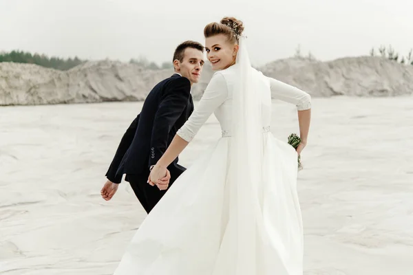 Щаслива наречена і наречений бігають і розважаються на піщаному пляжному озері — стокове фото