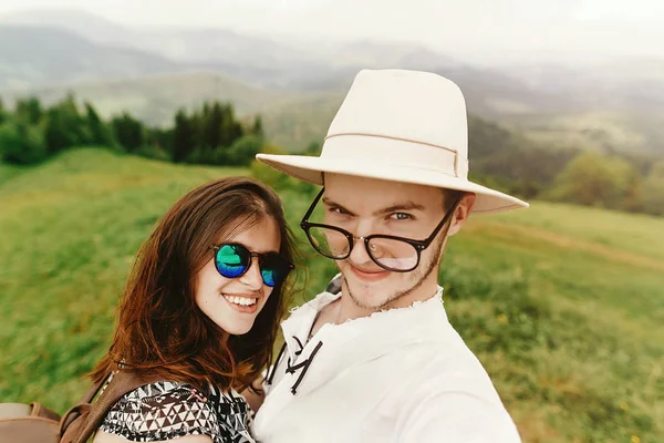 Elegante pareja hipster viajando y sonriendo en la cima de la montaña — Foto de Stock