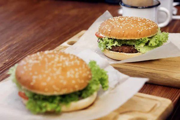 Deliciosas hamburguesas con ensalada en escritorio de madera —  Fotos de Stock