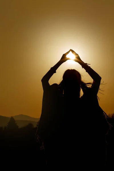 Silueta de las manos de mujer sosteniendo el sol — Foto de Stock