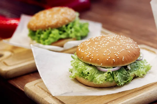 Deliciosas hamburguesas con ensalada en escritorio de madera —  Fotos de Stock