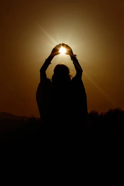 Силуэт женщины, держащей в руках солнце — стоковое фото