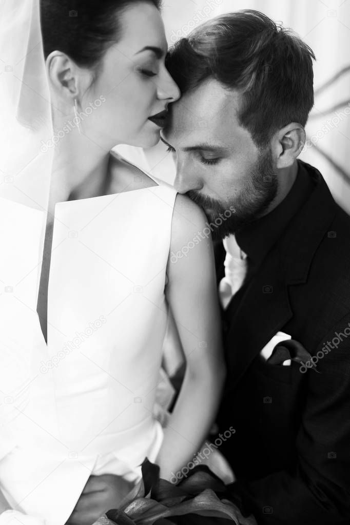 groom gently kissing in shoulder bride