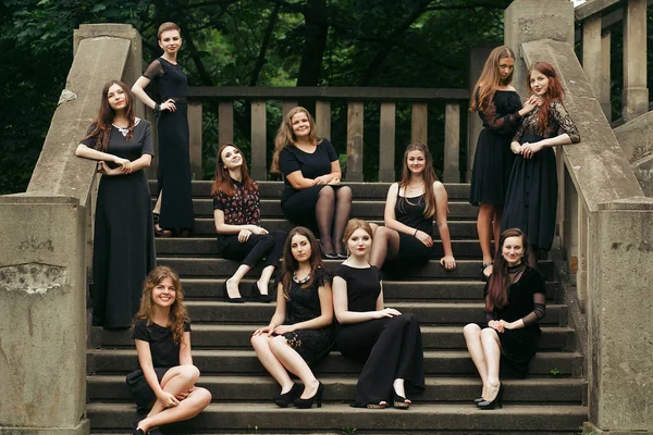 Grupa wspaniałej kobiety w czarnych sukniach pozowanie na schodach w PW — Zdjęcie stockowe