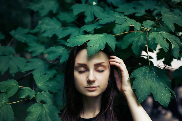 Yeşil yaprakları altında poz kız — Stok fotoğraf
