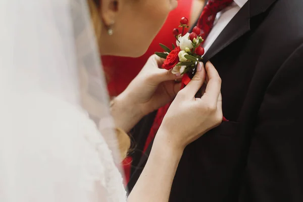Невеста кладет бутоньерку на жениха — стоковое фото