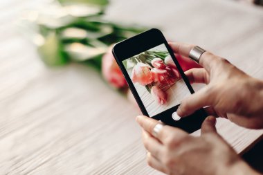 Çiçeklerin fotoğrafını çeken kadın.