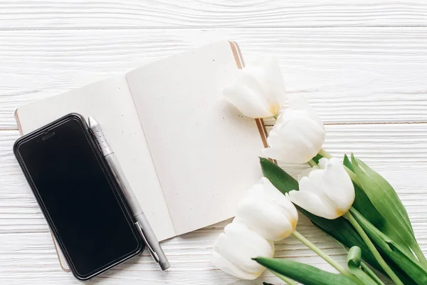 Phone screen, notebook, pen and tulips — Stock Photo, Image