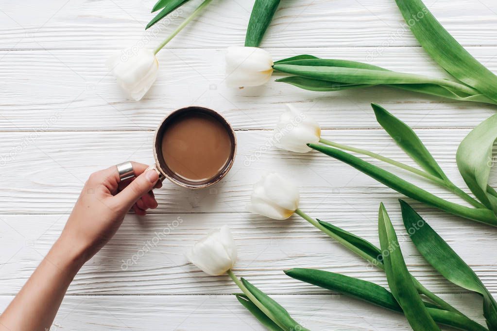 hand holding coffee cup and tulips