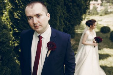 yaka çiçeği pos ile koyu mavi elbiseli damat