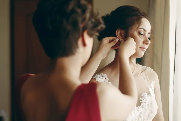 Подружка невесты помогает брюнетке невесте — стоковое фото