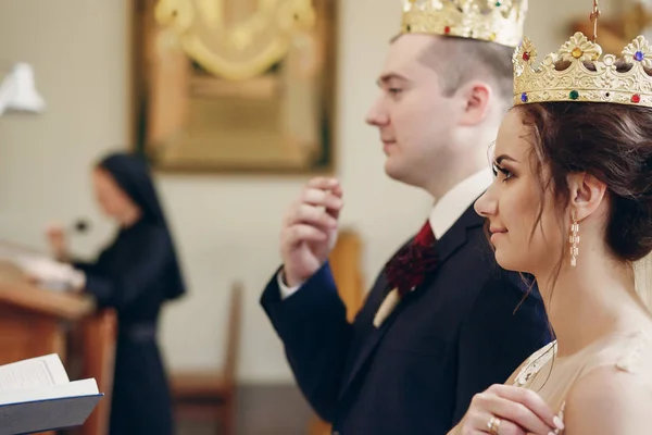 Bride and groom wearing gold crowns — Stock Photo, Image