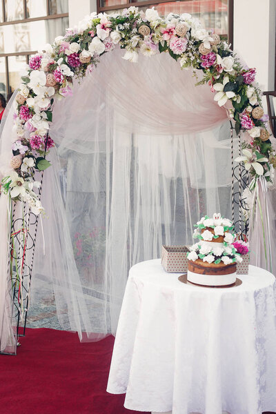 свадебный торт возле цветочной гирлянды
