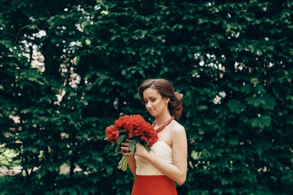 Brunette bride in dress holding flowers — Stock Photo, Image