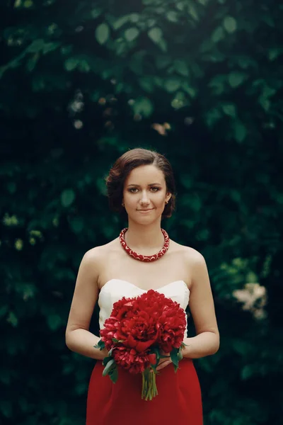 Mariée brune en robe tenant des fleurs — Photo