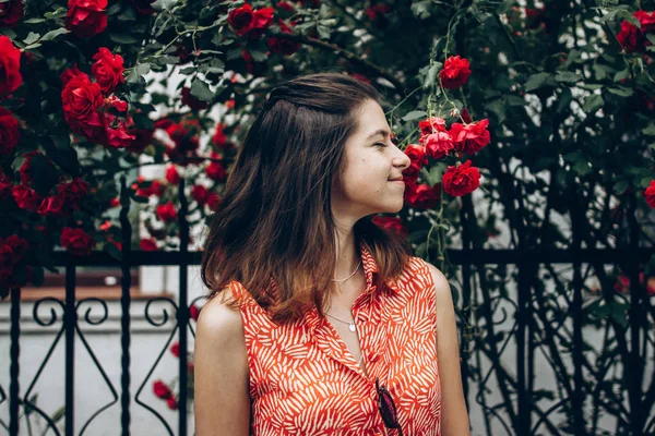 Girl smiling under big red roses — Stock Photo, Image