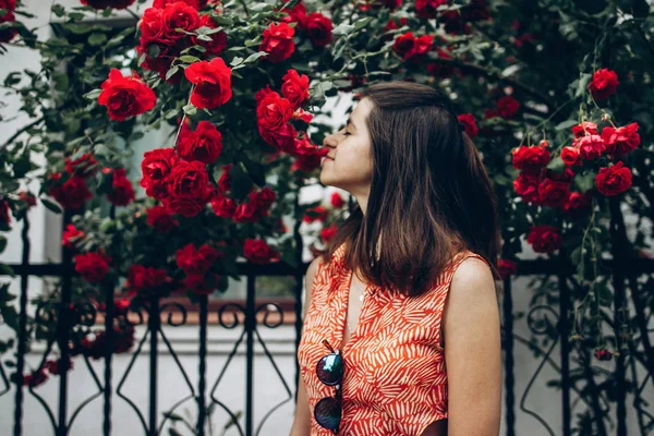 Дівчина посміхається під великими червоними трояндами — стокове фото