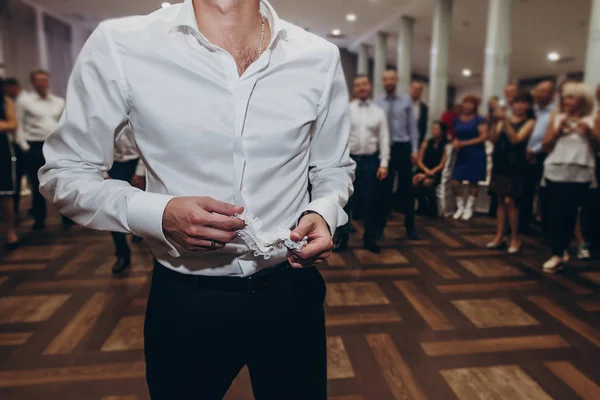 Brudgummen holding silk strumpeband underkläder — Stockfoto