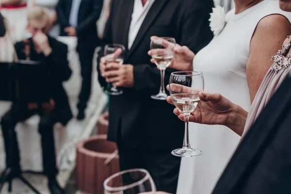 Taças de champanhe e vinho nas mãos — Fotografia de Stock