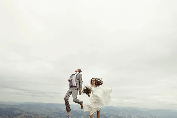 Recién casados saltando en las montañas —  Fotos de Stock