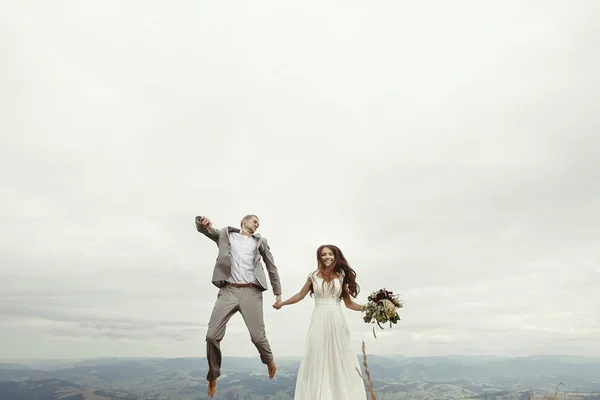 Recién casados saltando en las montañas —  Fotos de Stock