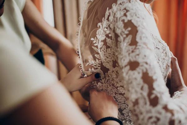 Tärnorna hjälpa bruden passar i klänning — Stockfoto